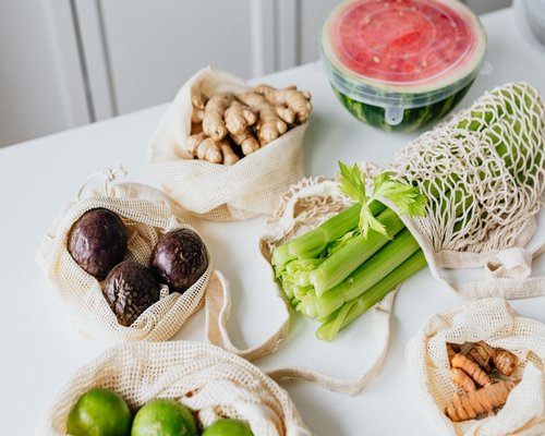 A variety of fresh vegetables, fruits, and legumes on a kitchen counter